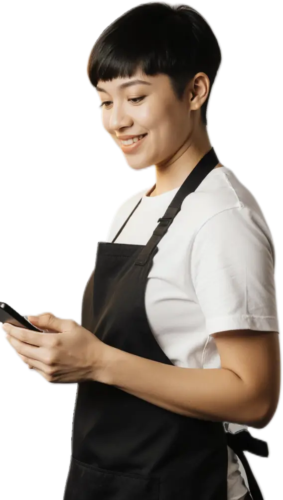 A barber smiles as she reads a message on her phone